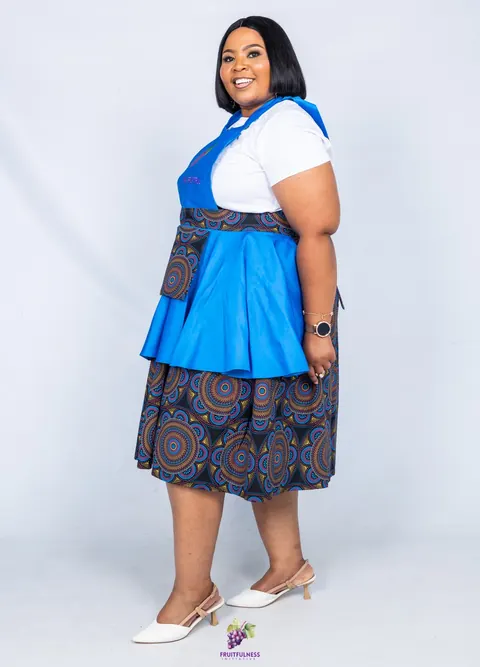 Side view of a woman in a blue apron with a mandala-print pocket and matching skirt